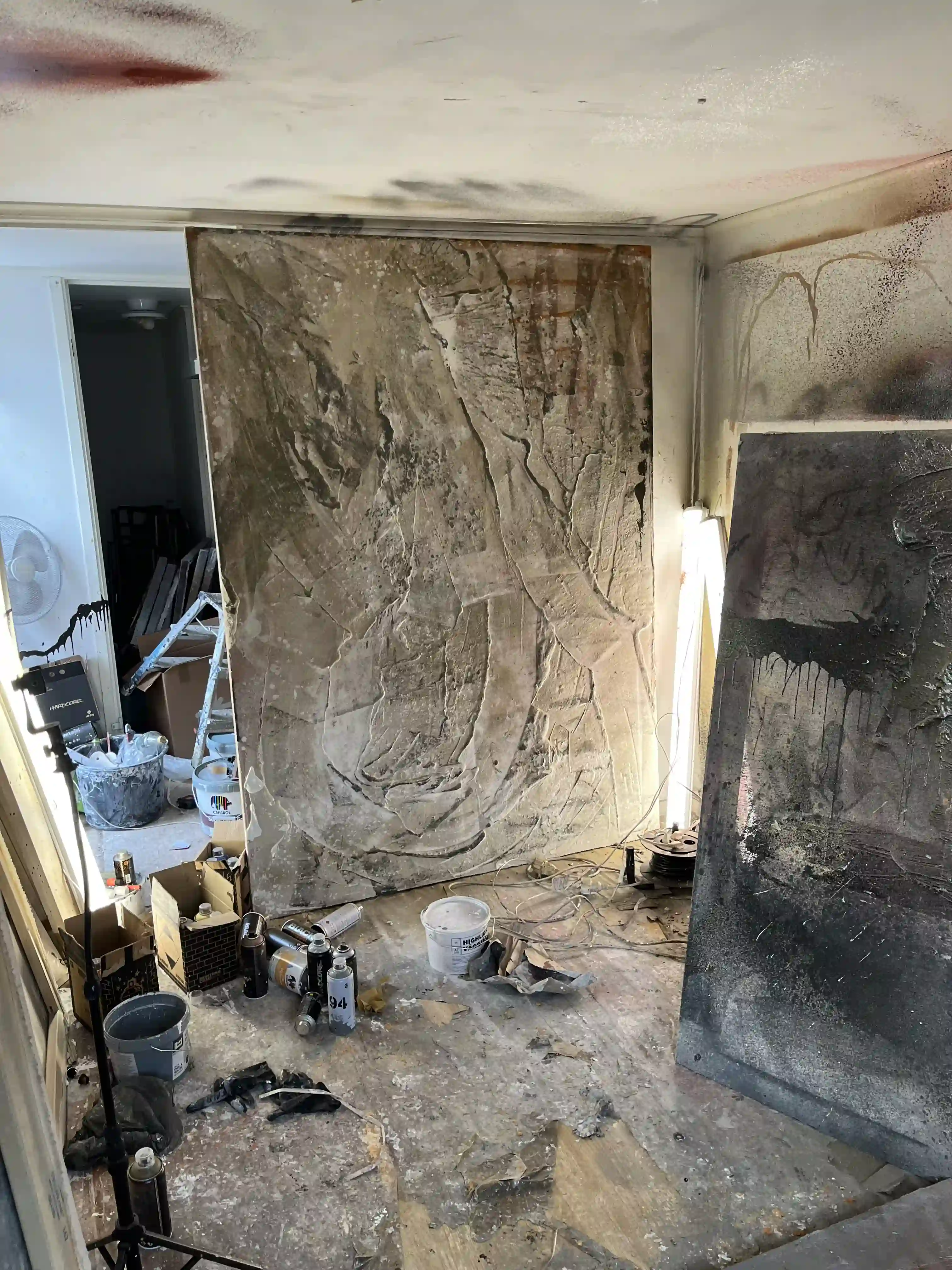 Canvas painting leaning against a studio wall, with materials scattered around